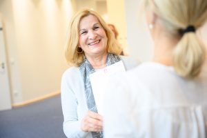 Radiologie MRT Radiologie, ältere Frau mit weißer Strickjacke lächelt ihre behandelnde Radiologin an, Befundbesprechung