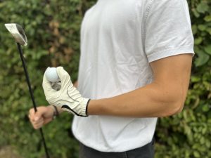 Golferarm: Symptome, Diagnose & Behandlung Bild eines Arms mit Golfhandschuh, Golfball und einem Eisen.