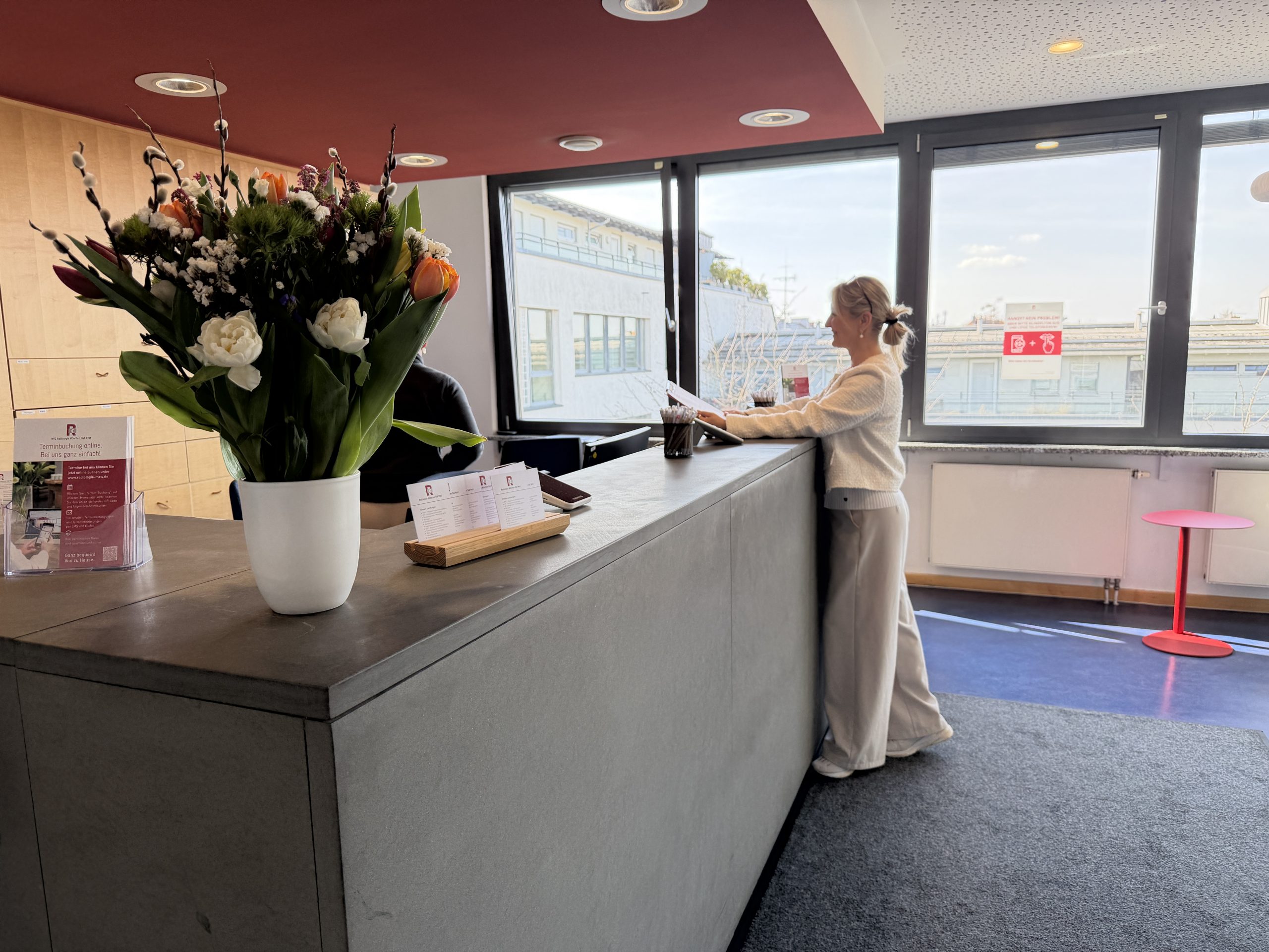 Schilddrüsen Untersuchung Radiologie München, patientin am Empfang, die Dokumente ausfüllt. bunte tulpen im vordergrund